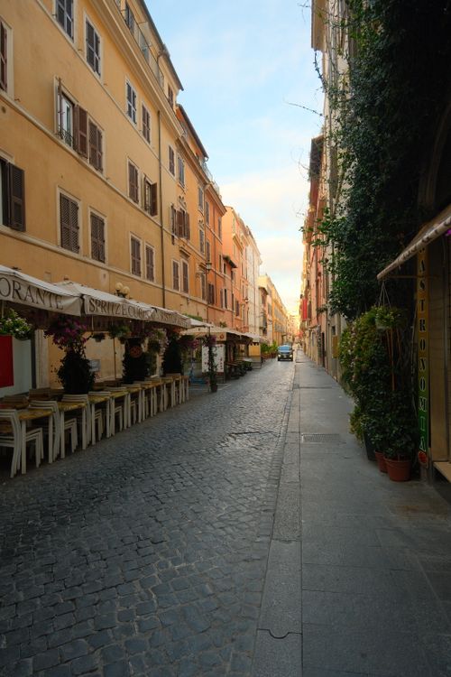 Free Peaceful cobblestone street in Rome, Italy with cafes and historic buildings. Stock Photo