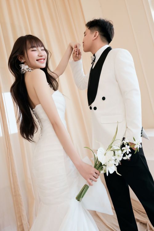 Free Happy bride and groom in stylish white attire sharing a romantic moment indoors. Stock Photo