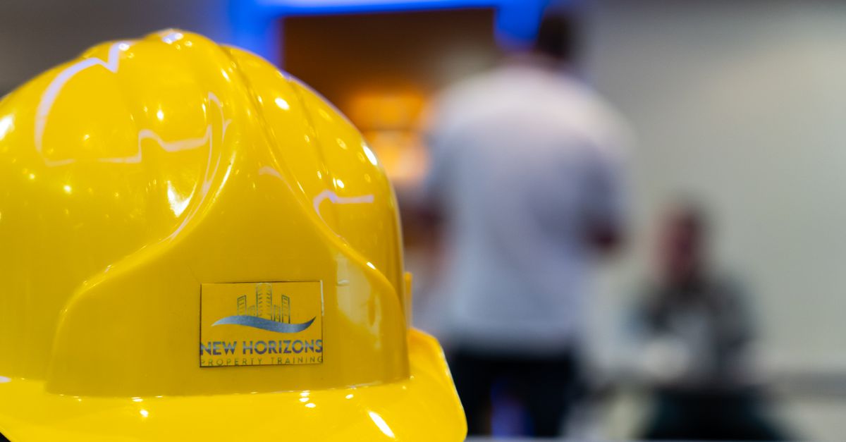 A yellow hard hat with New Horizons logo in a professional training setting.