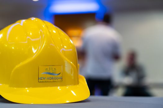 A yellow hard hat with New Horizons logo in a professional training setting.