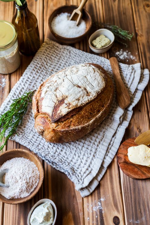 Free A rustic loaf of artisan bread displayed with ingredients on a wooden table, ideal for culinary themes. Stock Photo
