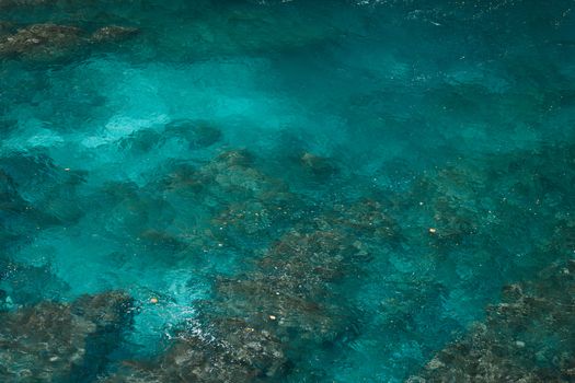 Top-down view of clear turquoise seawater and submerged reefs