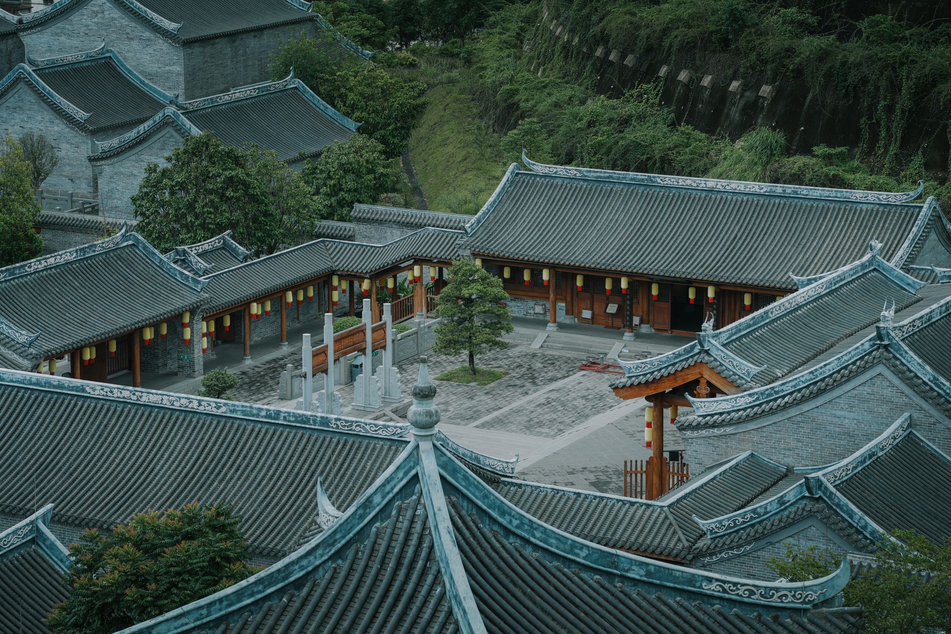 Aerial view of traditional Chinese temple architecture in Wuzhou, Guangxi, surrounded by lush greenery.