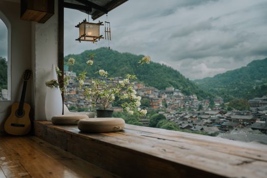 Cozy window nook with guitar and flowers overlooking ancient hillside village