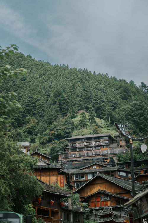 Free Scenic view of a traditional wooden village nestled in lush green hills of Guizhou, China on a cloudy day. Stock Photo