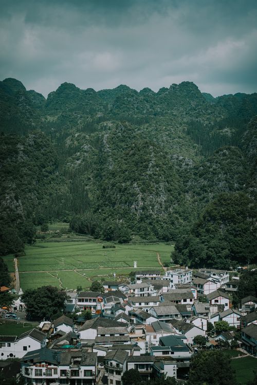 Free Explore the tranquil beauty of a village nestled in Guizhou, China, surrounded by lush green mountains. Stock Photo