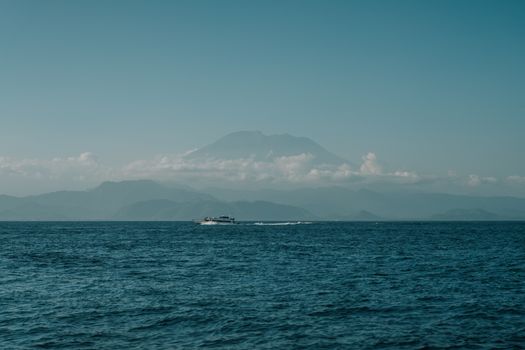 Serene ocean scene with a distant mountain range under a clear sky in Indonesia.