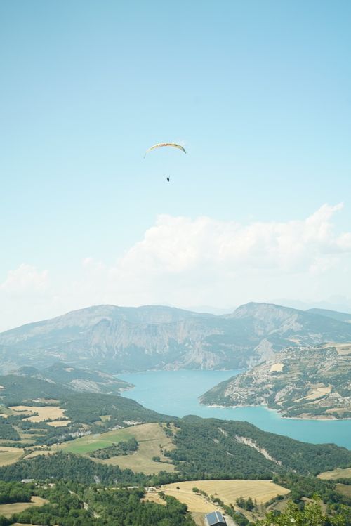 Free Breathtaking aerial view of a paraglider soaring over a beautiful mountain lake landscape. Stock Photo
