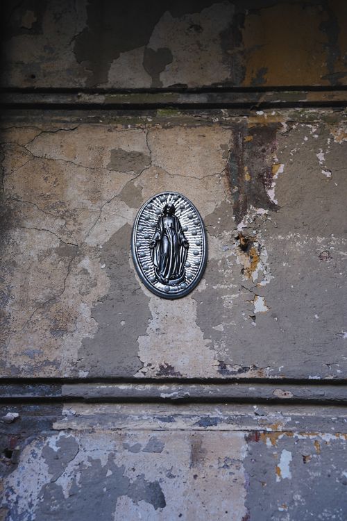 Free A religious metal plaque on an old, peeling wall in Warsaw, Poland. Stock Photo