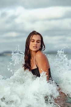 A woman in black swimwear embraces ocean waves, showcasing summer vibes in Ireland.