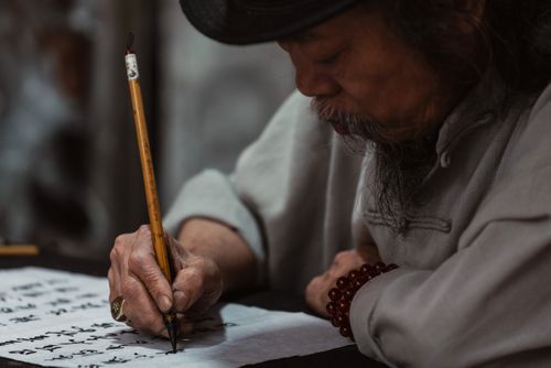 Free Elderly man practicing traditional calligraphy in Vietnam. Stock Photo