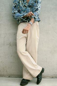 Stylish individual in beige trousers and patterned shirt, sporting a retro digital wristwatch for a chic vibe.