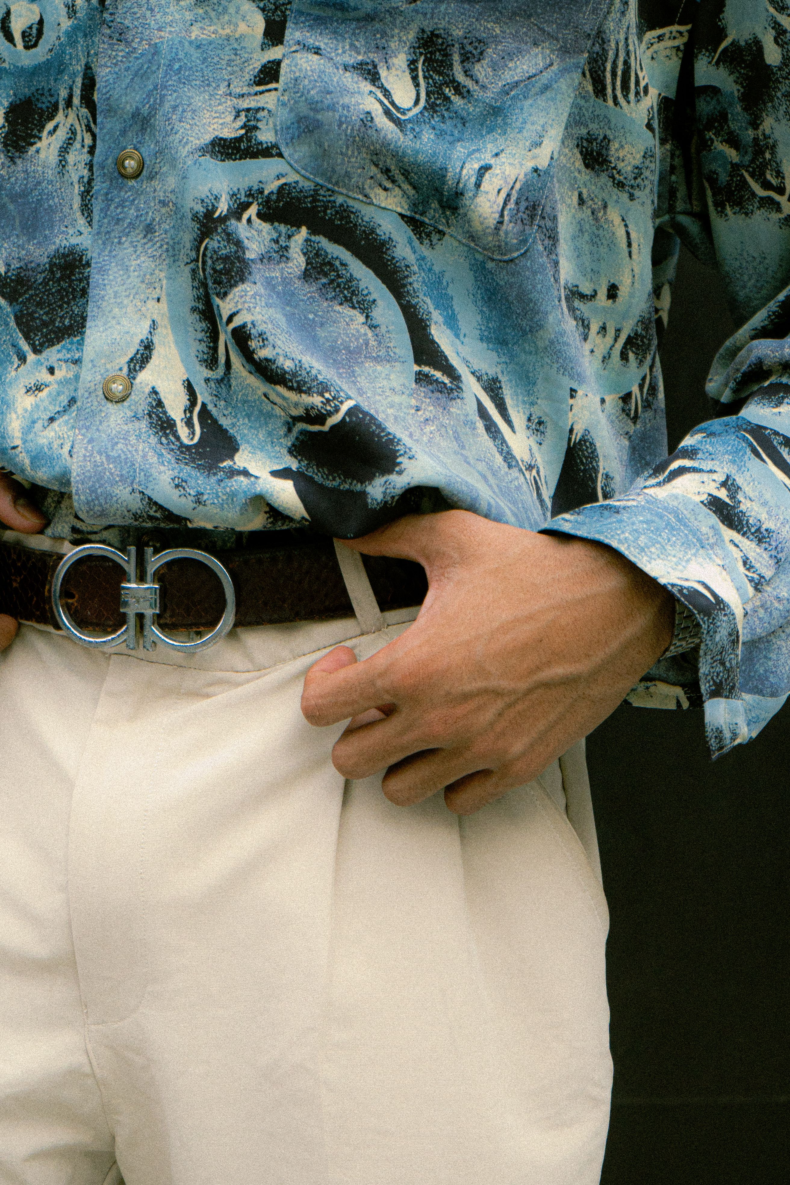 Man wearing an abstract blue shirt and beige pants showcasing modern men's fashion.