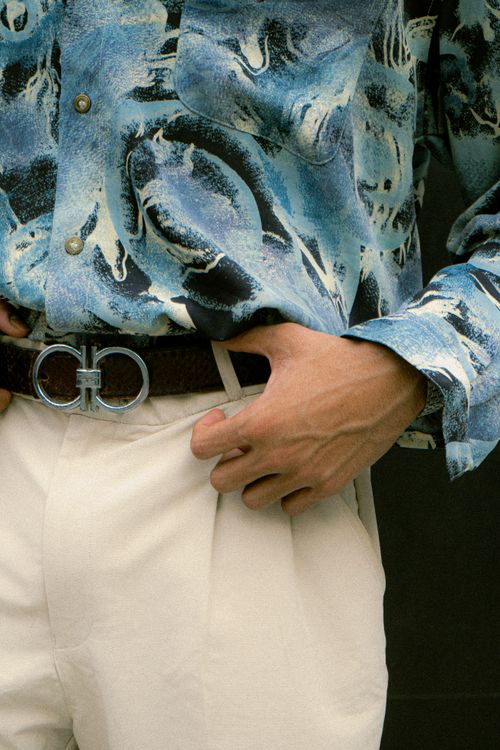 Free Man wearing an abstract blue shirt and beige pants showcasing modern men's fashion. Stock Photo