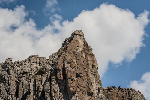 Free Dramatic mountain peak with rugged rocks against a backdrop of blue sky and white clouds. Stock Photo