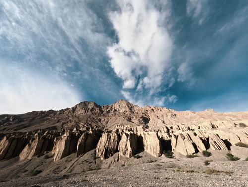 Free Stunning view of rocky cliffs and dramatic clouds over mountains under a blue sky. Stock Photo