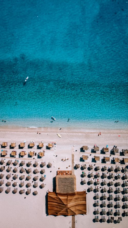 Free Stunning aerial view of a sunlit beach in Arnavutluk, featuring neatly arranged sunbeds and turquoise water. Stock Photo