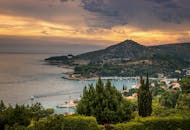 宁静的沿海景观中，山脉、大海与充满活力的日落天空交相辉映