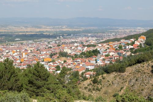 Free Aerial view of a sprawling city nestled between hills and forests under a clear sky. Stock Photo