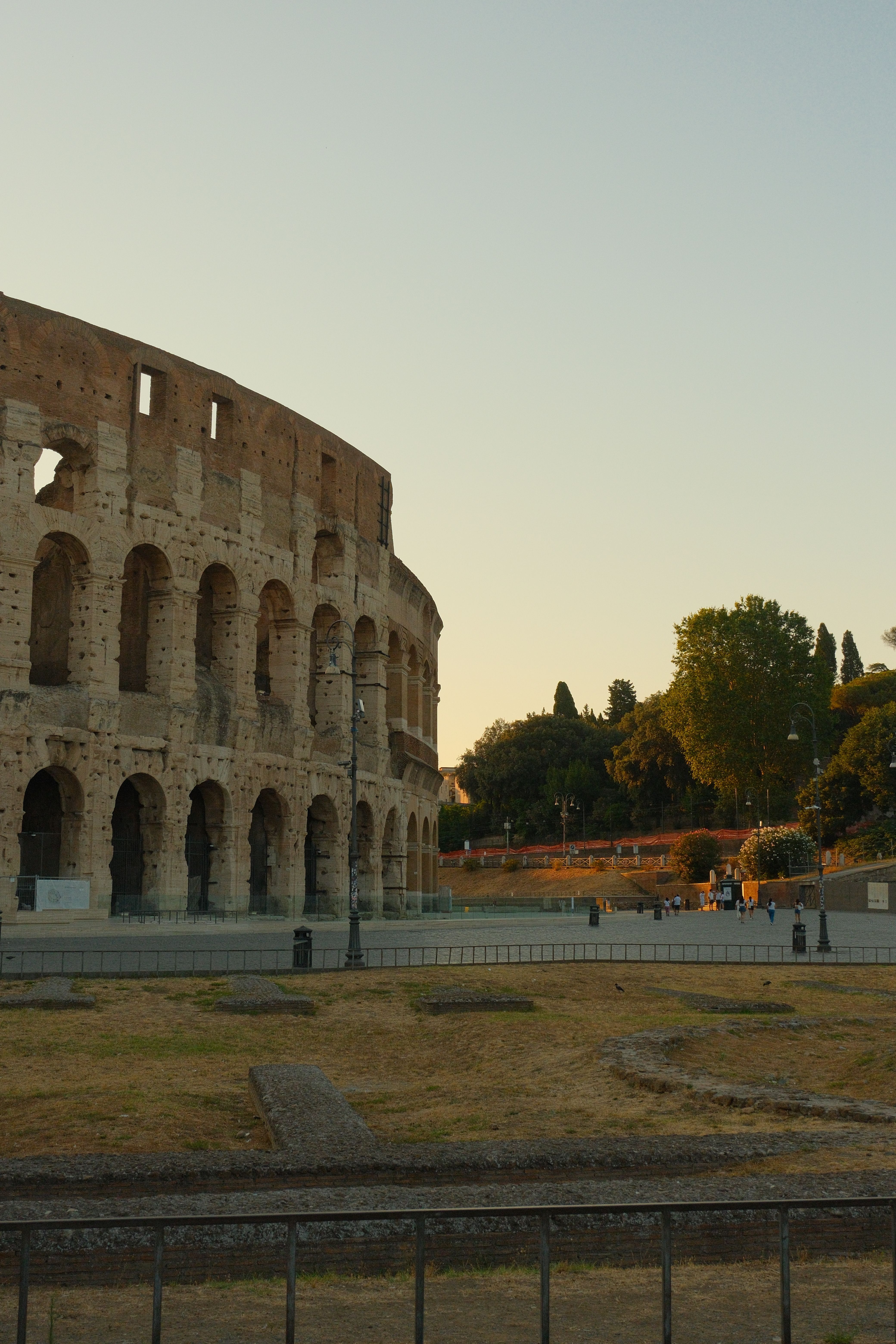 A serene evening view of the Roman Colosseum with warm lighting and minimal crowds.