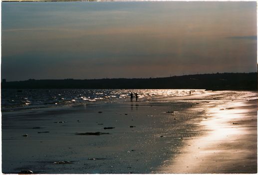 Captivating sunset over a tranquil beach in Lâm Đồng, Vietnam, with people silhouetted against the shimmering shoreline.