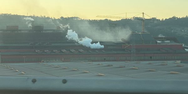 Site industriel avec vapeur montante et grue près de Bilbao, au crépuscule