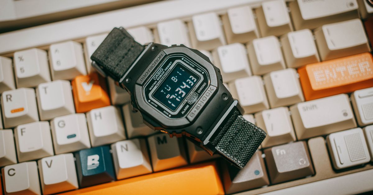 Close-up of a black digital watch resting on a mechanical keyboard with colorful keys.