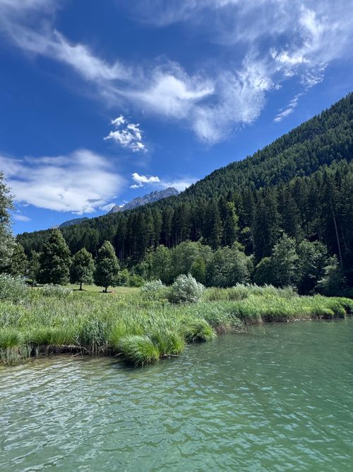 Free Beautiful alpine landscape in Tyrol, Austria, featuring a tranquil lake, lush forest, and majestic mountains under a blue sky. Stock Photo