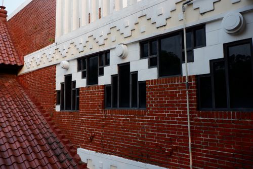 Free Close-up of red brick wall with unique window design and roof tiles. Stock Photo
