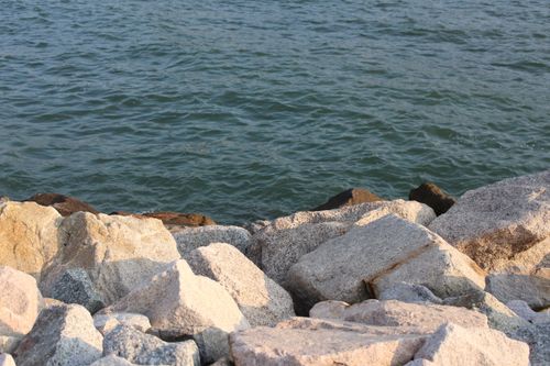 Free Close-up view of ocean waves against a rocky shoreline with large boulders. Stock Photo