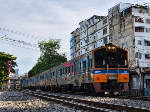 Free Train in Bangkok passing residential buildings, creating a dynamic urban scene. Stock Photo