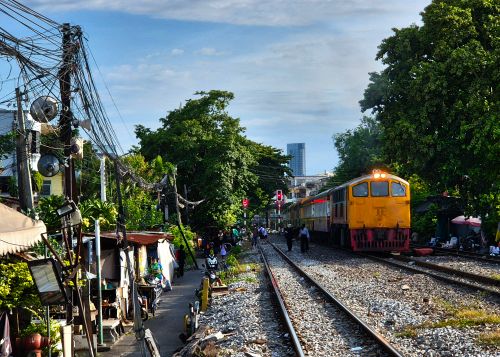 Free A vibrant scene of a train passing through a bustling district in Bangkok, Thailand. Stock Photo