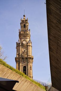 View of the iconic Clérigos Tower in Porto, Portugal, framed by modern architecture against a clear blue sky.
