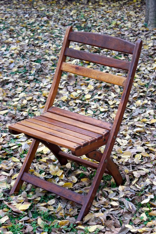 Free A wooden folding chair placed outdoors on a bed of fallen autumn leaves. Stock Photo
