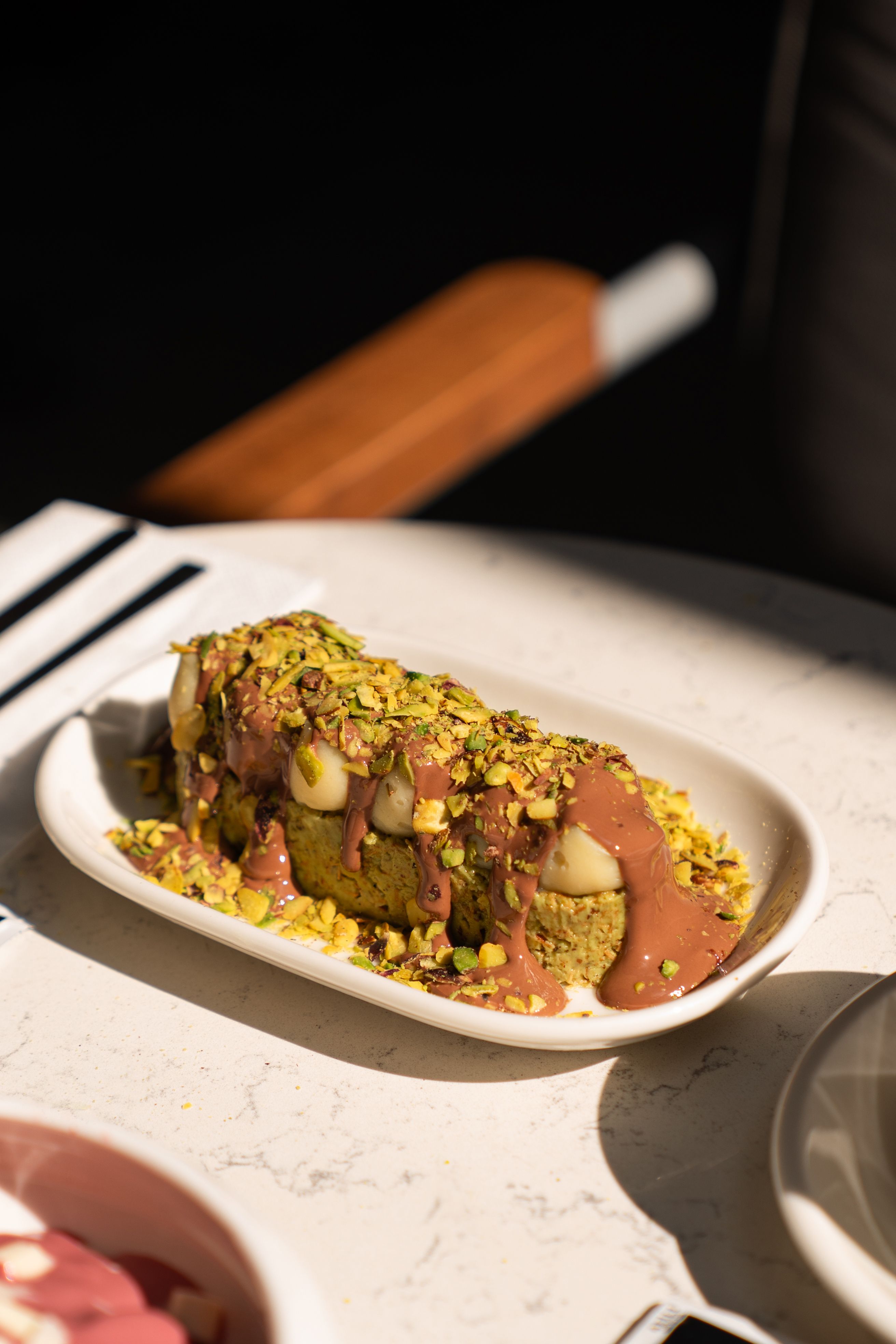 Elegant pistachio dessert drizzled with chocolate on a marble table, ideal for gourmet dining.