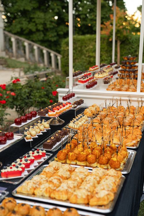 Free An elegant outdoor buffet showcasing a variety of gourmet desserts and pastries set in a picturesque garden setting. Stock Photo