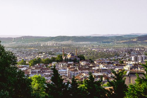 Free Aerial cityscape featuring a mosque and surrounding greenery with distant hills. Stock Photo