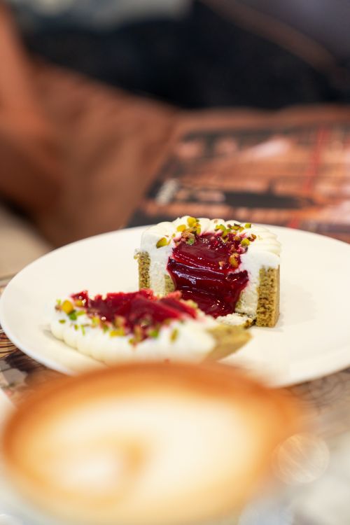 Free A close-up of a sliced pistachio dessert topped with berry sauce and cream, perfect for fine dining. Stock Photo