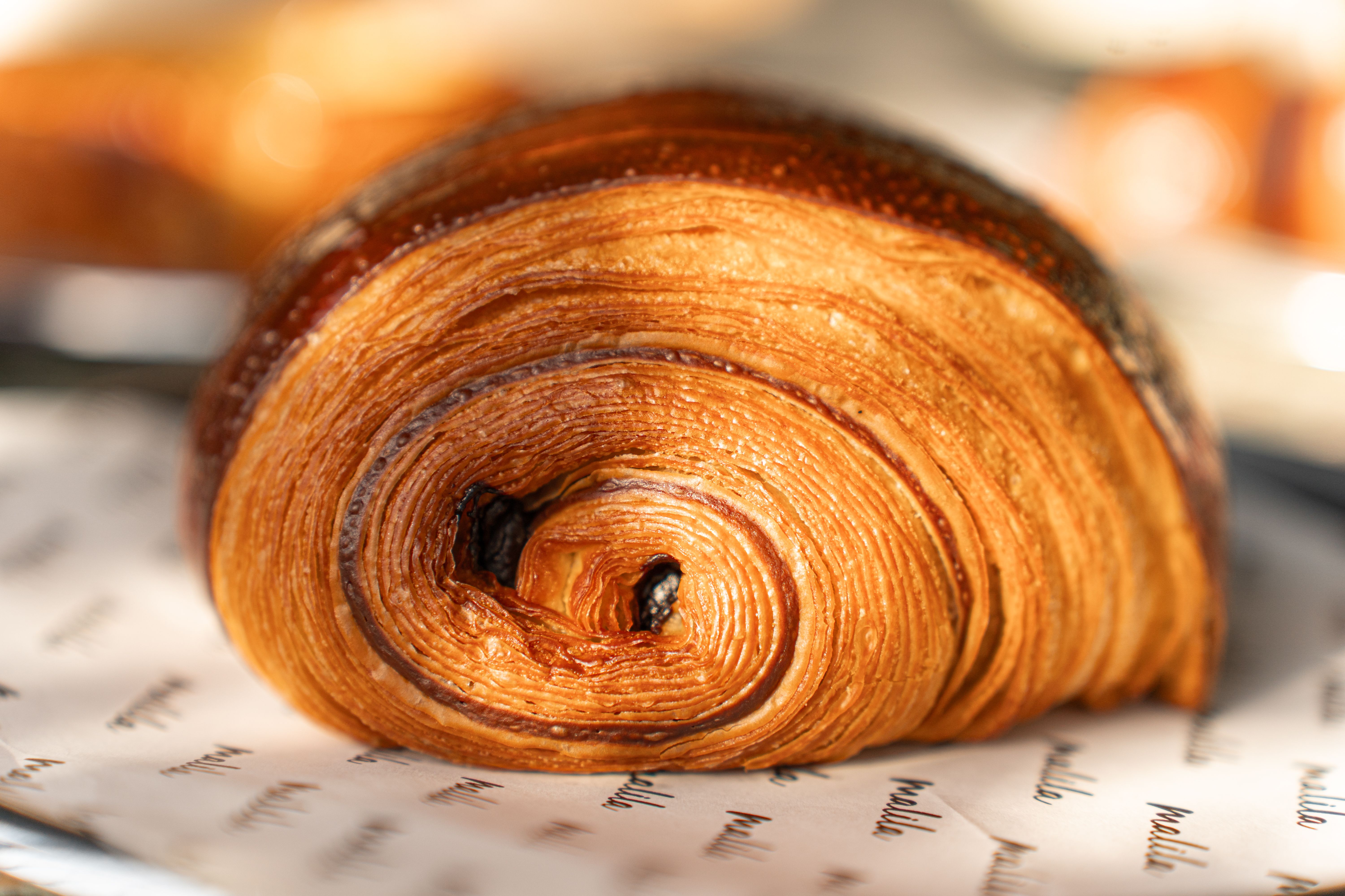 Delicious golden chocolate croissant on display, showcasing detailed flaky layers and rich texture.