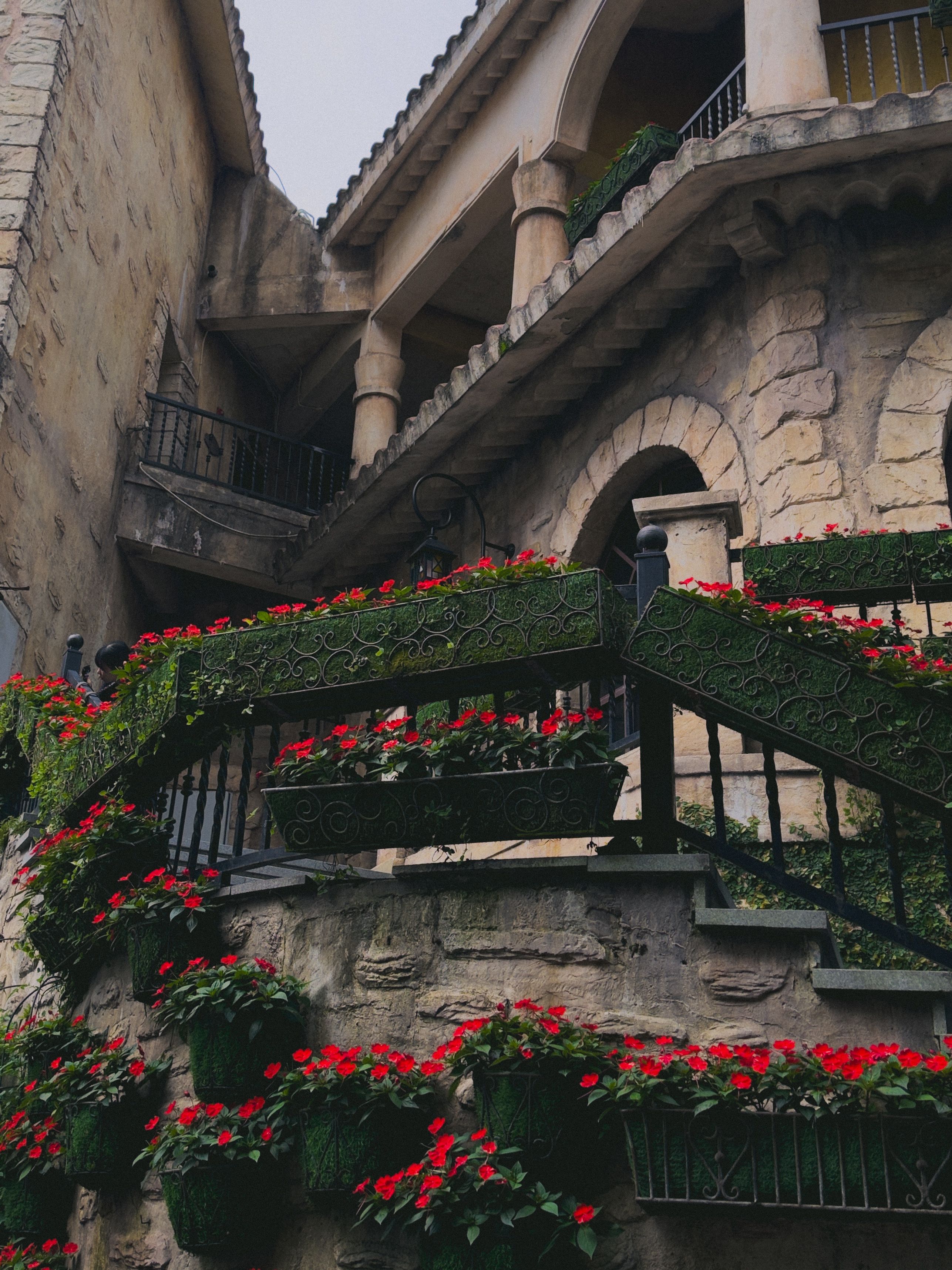 Picturesque stone staircase adorned with vibrant red flowers at Ba Na Hills, Đà Nẵng.