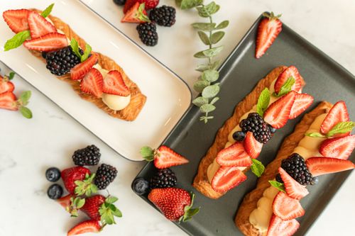 Free Delicious fruit tarts topped with fresh strawberries, blackberries, and mint on stylish plates. Stock Photo
