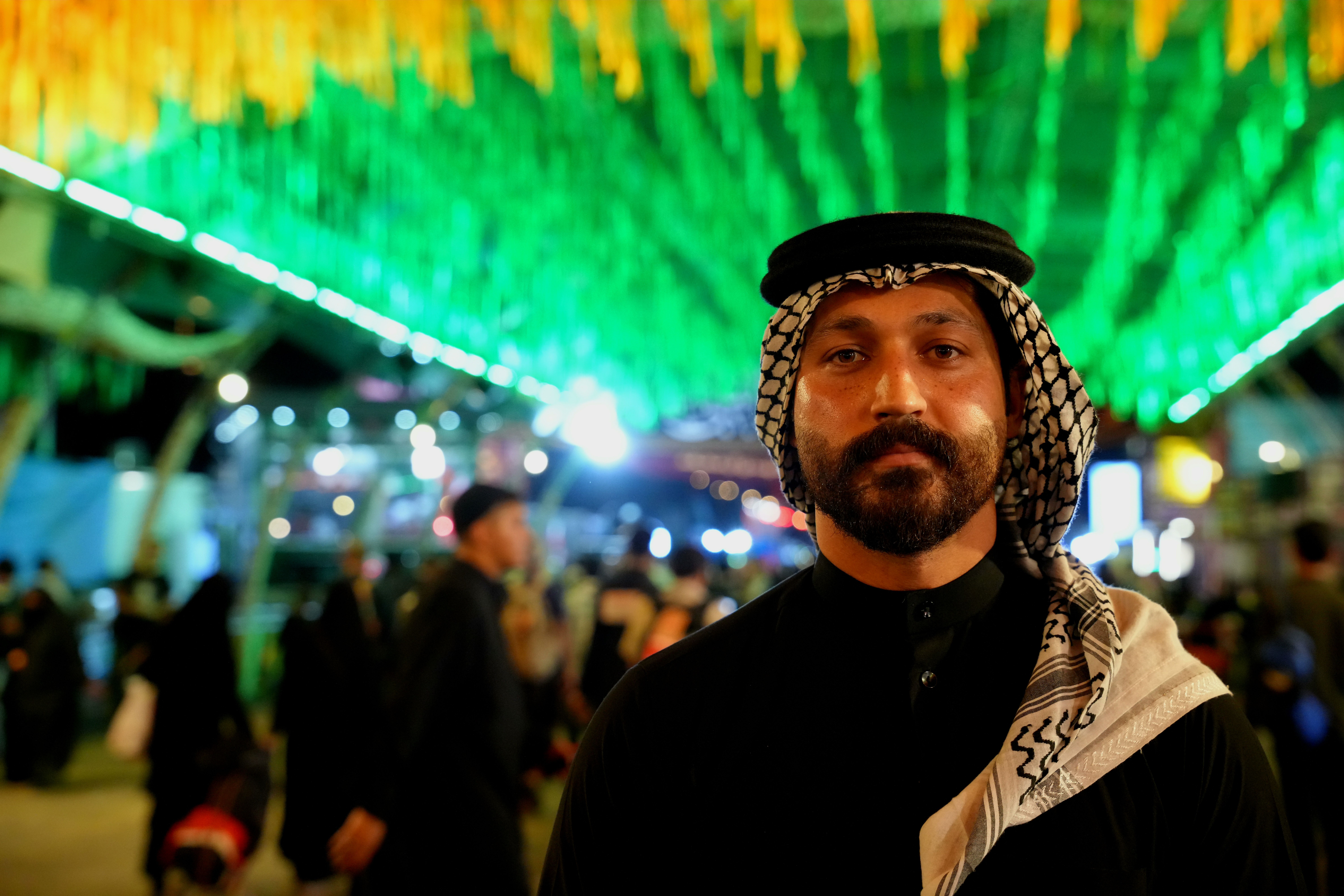Portrait of a man during Arbaeen pilgrimage in Karbala, Iraq, with vibrant lighting.