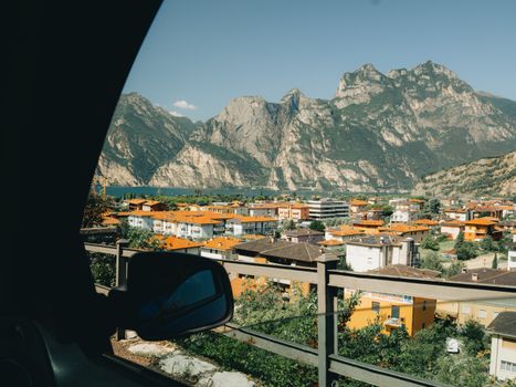 A stunning view of the Italian Alps and village rooftops seen from a car window, captured in daylight.