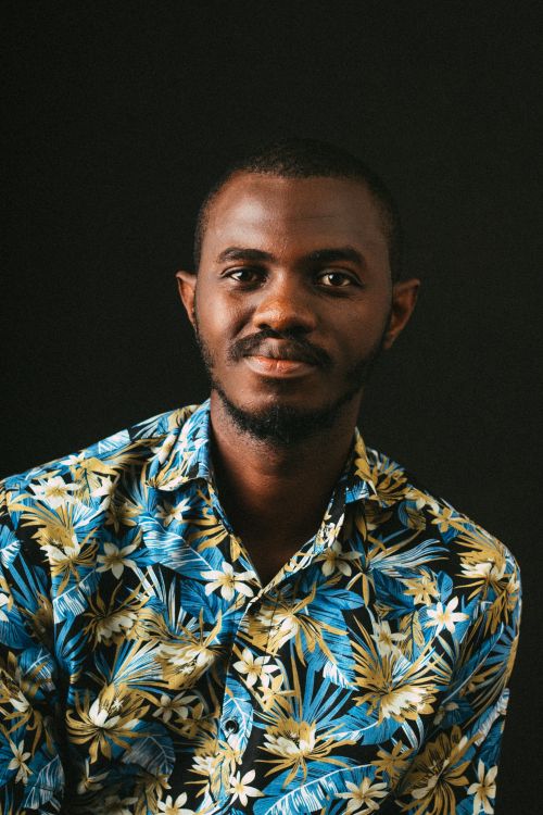 Free Studio portrait of a young man wearing a vibrant floral shirt against a dark background. Stock Photo