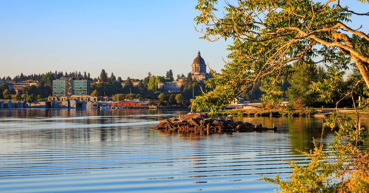 A picturesque view of the Washington State Capitol with calm waters and vibrant greenery in Olympia.