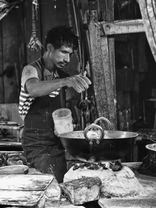 Free A street food vendor is cooking at a market in Kolkata, India. Black and white photo showcases local culinary tradition. Stock Photo