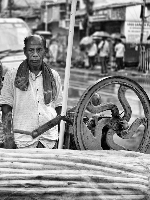 Free Black and white portrait of a street vendor using a sugarcane press in a bustling Kolkata street scene. Stock Photo