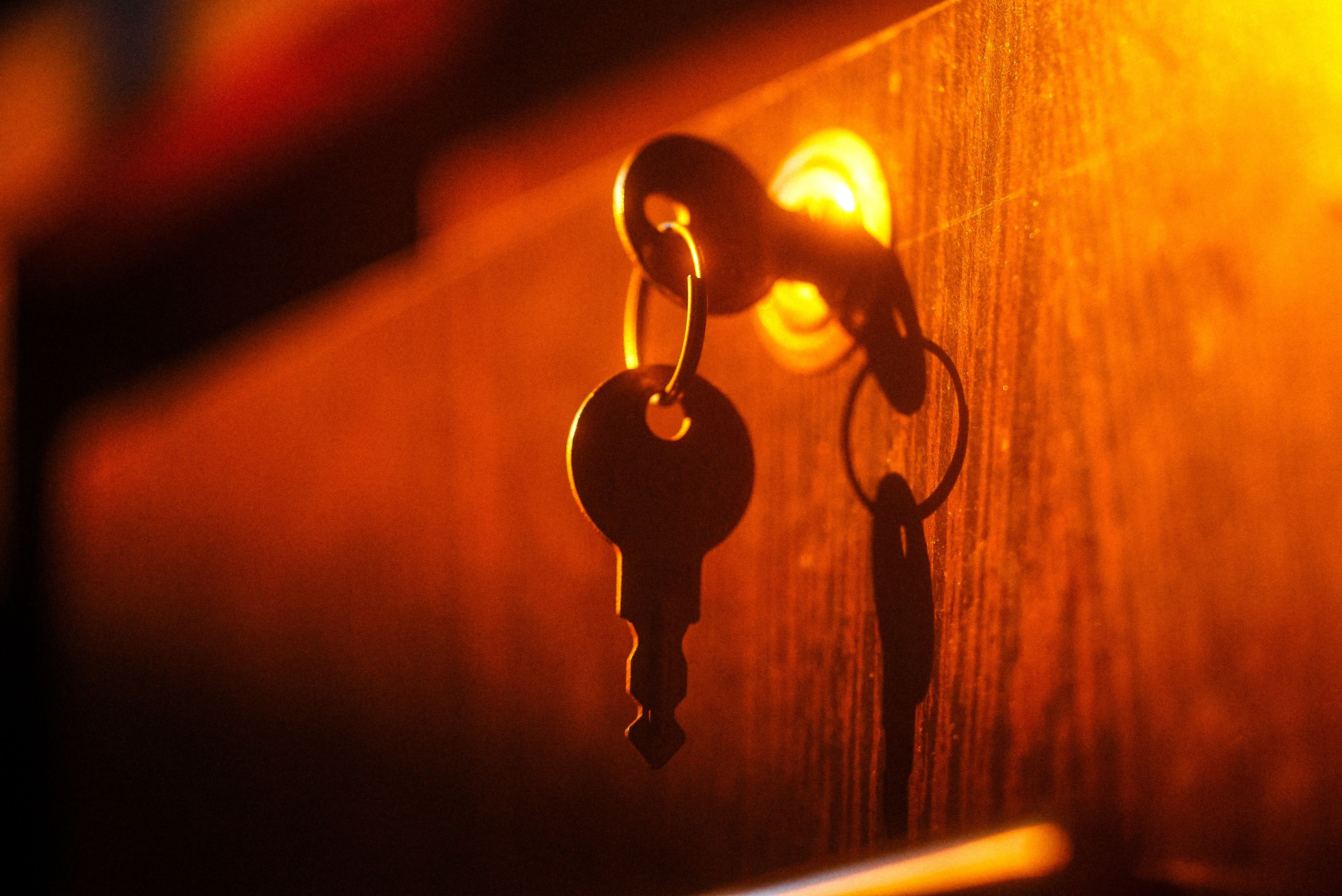 A close-up of a key in a lock with dramatic lighting and shadow play on a warm-toned wooden surface.