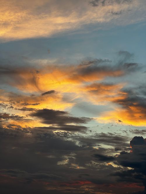 Free Vibrant sunset sky with dramatic clouds glowing in warm golden hues. Stock Photo