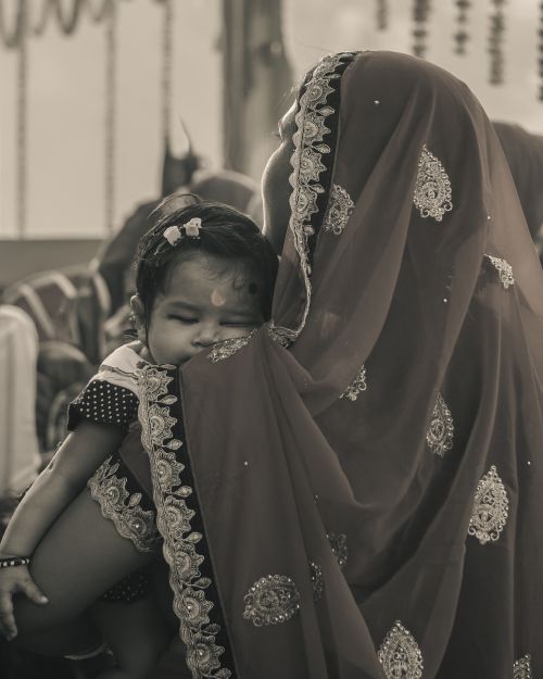Free A serene moment of a mother holding her child wrapped in intricate traditional fabric. Stock Photo